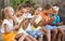 Group of glad children playing with mobile phones outdoors