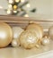 Group of glass Christmas ornaments on living room mantel with reflection of lighted Christmas tree in background. Simple, elegant