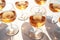 Group of glasses with amber wine, radiating a rich, deep orange hue on a white table. Scene emanates a luxurious yet minimalist