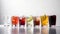 Group of glasses of fresh colored juice with fresh berries, fruits stand in row, white background. AI generated.