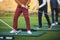 Group of golfers practicing and training golf swing on driving range practice, men playing on golf course, golf ball at golfing