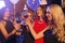 Group of gorgeous Caucasian young girls in elegant dresses smiling drinking wine toasting celebrating birthday in a cafe