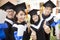 Group of graduating students holding diploma and thumb-up