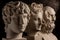 Group gypsum busts of ancient statues human heads for artists on a dark background. Plaster sculptures of antique people