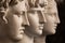 Group gypsum busts of ancient statues human heads for artists on a dark background. Plaster sculptures of antique people