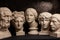 Group gypsum busts of ancient statues human heads for artists on a dark background. Plaster sculptures of antique people