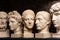 Group gypsum busts of ancient statues human heads for artists on a dark background. Plaster sculptures of antique people