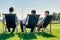 Group of handsome businessmen relaxing and talking about life while sitting on folding chair at park
