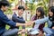 A group of happy Asian college students sitting in the park, putting their hands together, cheering up