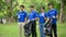 A group of happy Asian volunteers in uniform stand in a public park with plastic garbage bags