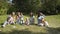 Group of happy children playing outdoors in the summer Park. Mothers look after their children sitting on the grass.