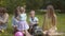 Group of happy children playing outdoors in the summer Park. Mothers look after their children sitting on the grass.