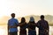 Group of happy friends are having fun with raised arms together in front of mountain and enjoy sunrise sunset showing unity and