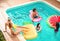 Group of happy friends relaxing in swimming pool - Young people having fun floating on air lilo during summer tropical vacation