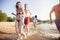 Group of happy friends running in to water - active people having fun on the beach on vacation