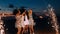 Group of happy girlfriends dancing between fireworks at night