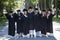 Group of happy graduates in robes outdoors.