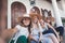 Group of happy joyful young stylish girls travel together, in hats against the