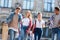 group of happy multiethnic teenagers with backpacks having walk together with old school building