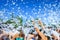 Group of happy people raise their hands during a foam party in summer to play with soap bubbles