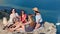 Group of happy relaxed young travel woman enjoying break having picnic on top of mountain over sea