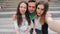 Group of happy teen friends laughing and taking a selfie in the street. Three friends watching taking pictures with