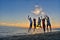 Group of happy young people is running on background of sunset beach and sea