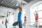 Group of healthy woman training together and doing fit exercise in white gym. People practice yoga poses together indoor