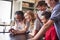 Group Of High School Students Looking At Message On Mobile Phone In Classroom