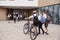 Group Of High School Students Wearing Uniform Arriving At School Walking Or Riding Bikes Being Greeted By Teacher