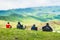 Group of hikers with backpacks sit enjoy panorama of caucasus mountains after long hike outdoors in spring