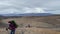 A group of hikers with backpacks and trekking poles are walking along the endless tundra.