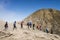 Group of hikers walk in line on mountain slope