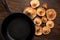 Group inverted fresh raw edible mushroom, Lactarius, on wood background near black iron cast pan left. Top view, space