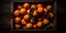 Group of juicy oranges arranged in a wooden crate, set against a dark background with a top-down view.