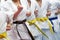 A group of karateka in white kimonos with yellow, blue and brown belts. Warm up during training. Active lifestyle