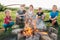 Group of Kids - Boys and girls cheerfully smiling and roasting sausages on sticks over a campfire flame Sausages selective focus.