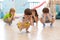 Group of kids squatting on floor in daycare, having fun and playing hide and seek game, hiding the face with hands