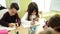 Group of kids students sitting on table drawing on notebook at classroom