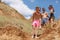 A group of laughing friends stands on a field, beautiful girls and boys on a vacation on a natural blurred background.