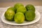 Group of lemons on plate and white tablecloths on the table.