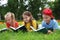 Group of little children reading books on green grass