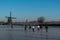 Group of locals on a frozen windmill canal pathway at sunrise moment