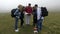 Group of lost young tourists hiking looking for direction trough fog reading the map on a mountain top -