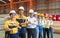 Group of male and female factory labor stand smiling together with arms crossed in industry factory. Everyone wearing safety