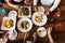 Group of male and female friends having dinner and eating steak and salad and spaghetti together in restaurant - top view.