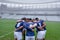 Group of male rugby players forming huddles in the morning