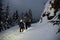 Group of male skiers walking along trail on snowy mountain against the background of snow-covered fir trees