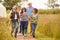 Group Of Mature Friends Walking Along Path Through Yurt Campsite