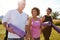 Group Of Mature Men And Women With Exercise Mats At End Of Outdoor Yoga Class